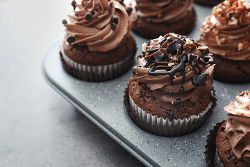 Muffin tin with tasty chocolate cupcakes on grey background, closeup