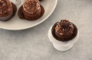 Stand with tasty chocolate cupcake on table