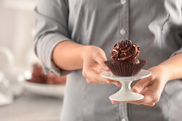 Woman holding stand with tasty chocolate cupcake, closeup