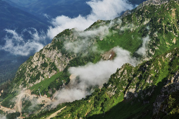 Panorama of the mountains in the area of Krasnaya Polyana/Panorama of Sochi in the Krasnaya Polyana area. There are mountains, clouds, air haze, vegetation. Sochi, Russia, mountain landscape 