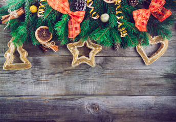 Vintage Christmas background with fir branches, new year decor, toys, candied fruits and spices on the old rustic wooden backdrop. Top view with copy space. Selective focus,