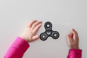 Kids hands playing with fidget spinner toy on white background. Top view