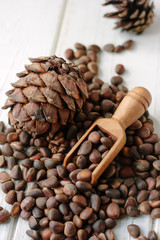 Cedar nuts in wooden scoop over heap of cedar nuts.