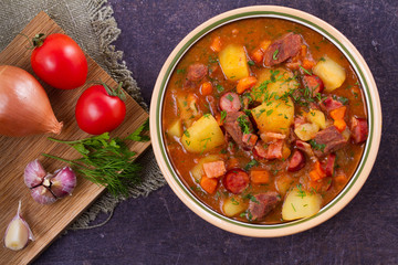 Stew, made with beef, bacon, sausages potatoes, carrots and herbs. Goulash soup bograch in a bowl. Hungarian dish