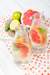 Infused flavored water with fresh fruits on white wooden background.Refreshing summer homemade  detox water