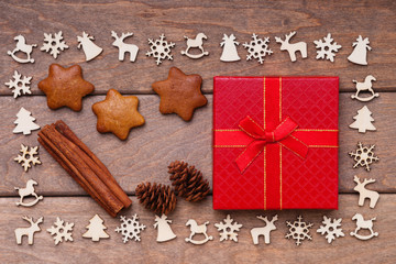Christmas decoration over wooden background, gingerbread cookies, cinnamon, fir tree cone and gift box 