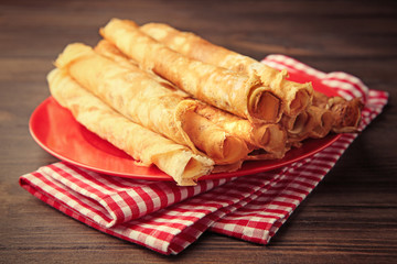 Plate with delicious thin pancakes on table