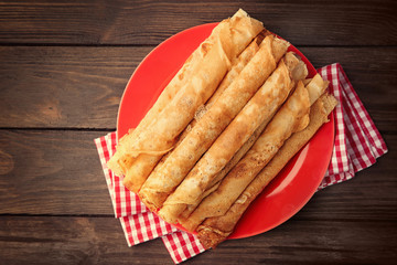 Plate with delicious thin pancakes on table