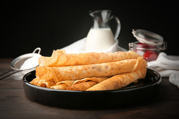 Plate with delicious thin pancakes on table