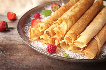 Metal plate with delicious thin pancakes on kitchen table