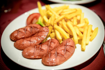 Large dish of delicious French Alsatian cervelas sausages with fries on a plate in a traditional French restaurant 