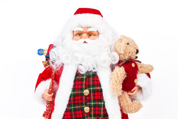 Studio portrait of Santa Claus doll with presents. Studio shot of cute grandfather frost holding plush teddy bear isolated on white background. Traditional symbol of New Year and Christmas.