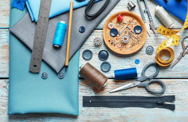 Set of tailoring tools, accessories and fabric on table, top view