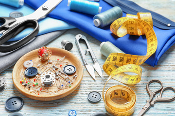Set of tailoring tools, accessories and fabric on table, closeup
