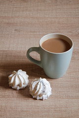 A cup of coffee with a biscuit in white chocolate on a wooden background