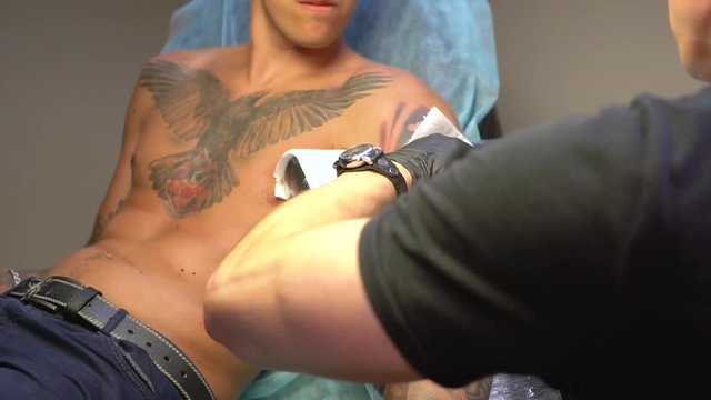Tattoo master performs disinfection tattoo on the hand image of a drummer and drumsticks