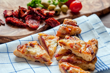 Round sausage pizza Margarita cut into pieces to feed the cloth with sun-dried tomatoes . Selective focus.