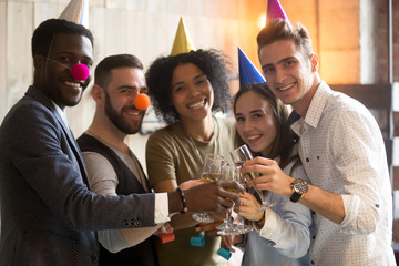 Diverse african and caucasian people clinking champagne glasses, happy multi-ethnic friends celebrate New year day eve or birthday party together, smiling multiracial group looking at camera portrait