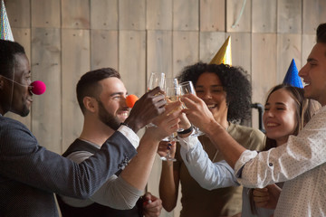 African and caucasian young friends clinking glasses celebrating party together, diverse people in...