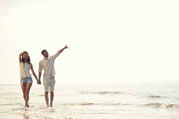 Happy fun beach vacations couple walking together laughing having fun on travel destination.