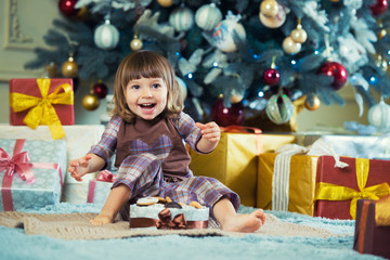 Happy little girl opens a box with a gift for Christmas.