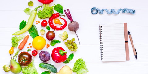 Diet, detox planning new year concept - fresh vegetables and fruits in the form of christmas tree. Notebook, measure tape on the white wooden background. Top view. Selective focus. space for text.