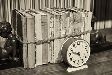 Old books tied up with rope and alarm clock