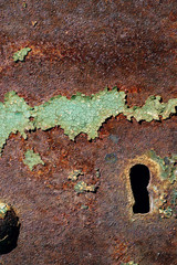 Fototapeta na wymiar texture of rusty iron, cracked green paint on an old metallic surface, metal surface with a bolt and a keyhole