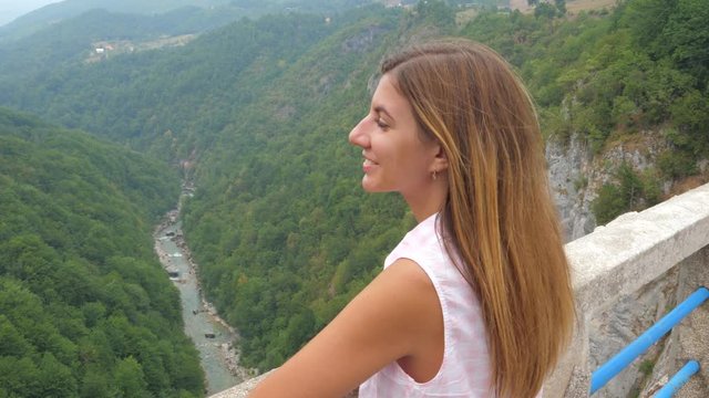 Young Woman Looking At The Mountains Standing On A Bridge Over A Deep Canyon