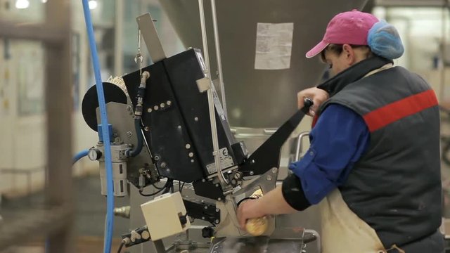 Worker produces sausage on a automated food production equipment