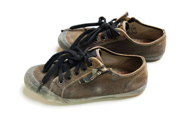 Old and dirty black school boy sneakers isolated on white background