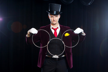 magic, performance, circus, show concept - magician in top hat showing trick with linking rings