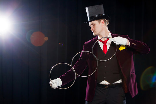 magic, performance, circus, show concept - magician in top hat showing trick with linking rings