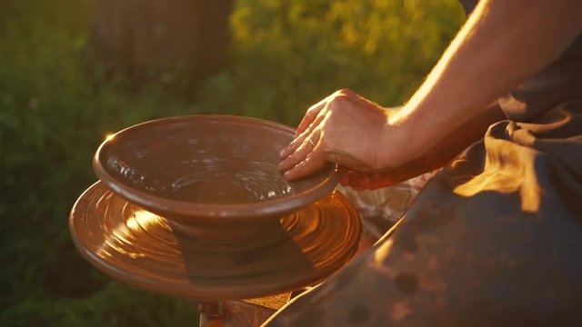 Male potter&rsquo;s hands taking a fresh clue in bright light, to create a vessel. Creation, traditions, customs. Positive mood, being happy. Camera stabilizer shot, male portrait, close up view