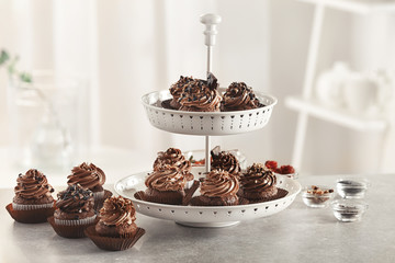 Dessert stand with tasty chocolate cupcakes on table