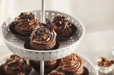 Dessert stand with tasty chocolate cupcakes on blurred background