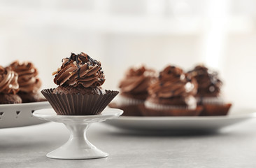Stand with tasty chocolate cupcake on table