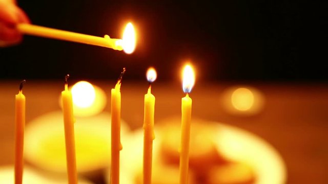 a woman holds a candle in her hand with the help of which she lights candles of Hanukkah. a woman lights candles from the first candle from right to left. close-up. 