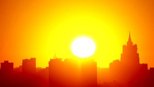 The great yellow sun rises above the spiers of the high city houses