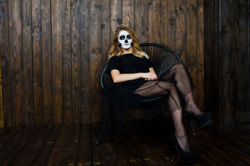 Halloween skull make up girl wear in black against wooden wall at studio.
