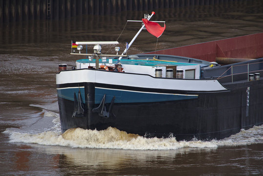 Bow of inland vessel running at high speed with white foaming bow wave