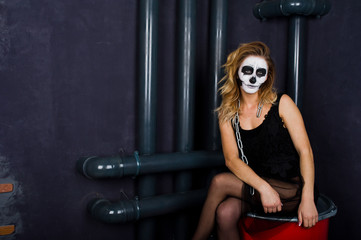 Obraz na płótnie Canvas Halloween skull make up girl wear in black against sitting on red barrel at studio.