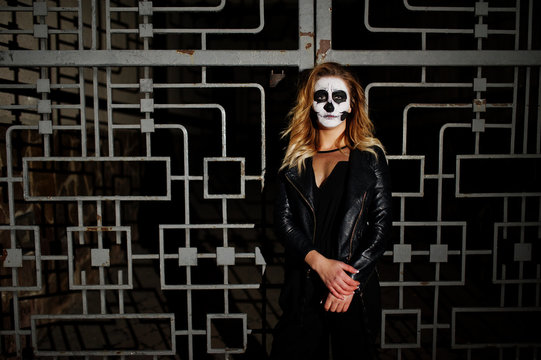 Halloween skull make up girl wear in black at night street of city against cage.