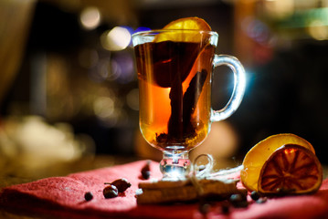 A glass of mulled wine on a bar counter with lemon and a cinnamon stick