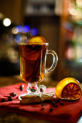 A glass of mulled wine on a bar counter with lemon and a cinnamon stick