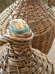 Obraz premium glass demijohn wrapped in straw basket traditional alcohol different liquids storage