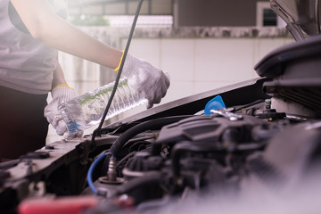 Mechanic fill fresh water into windscreen or in water tank wiper on car engine room