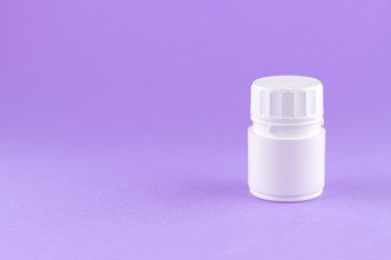 Close up white pill bottle on purple background with copy space. Focus on foreground, soft bokeh. Pharmacy drugstore concept