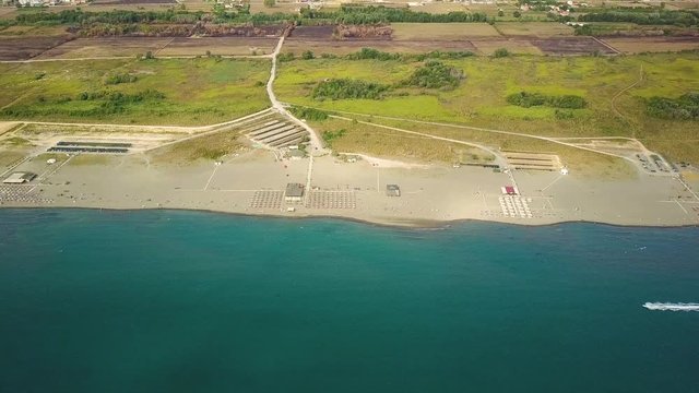 Motor boat moves along long sandy beach at a sea shore. Aerial view of Velika plaza, Montenegro