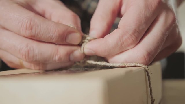 close-up of tying the twine on the bow. packing of finished products butterfly tie made of wool. Good looking young man working as a tailor and using a sewing machine in a textile studio.